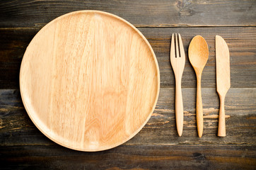 kitchenware (wooden spoon,fork and plate) on wooden background