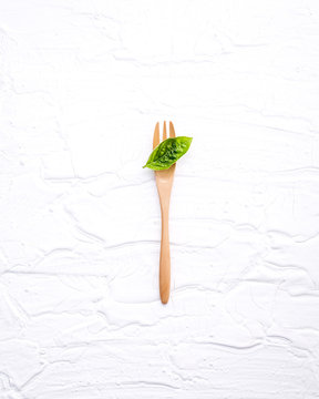 Closeup  fresh sweet basil leaves with fork  on white wooden bac