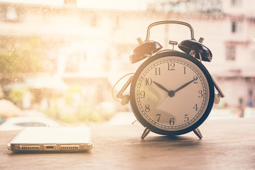 Naklejka premium Alarm clock, coffee smartphone is placed on a wooden table in a coffee shop
