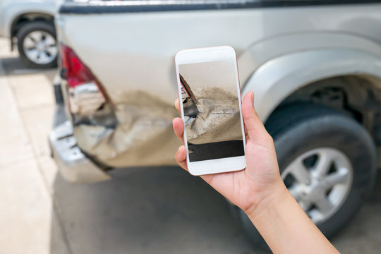 woman using smart phone to take car damage photo