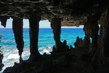View to the ocean from a cavern with stalactites and stalagmite in a cliff on the sea shore, Rurutu island, south Pacific, Austral archipelago, French Polynesia