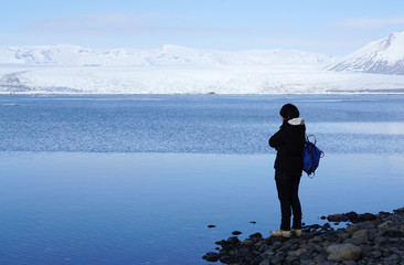 Fototapeta na wymiar Human standing on the edge of the water with snow mountain backg