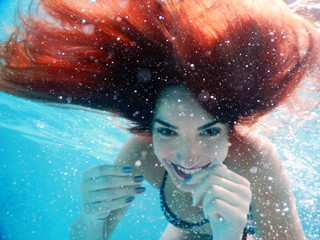 young happy woman portrait underwater by the pool