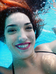 young happy woman portrait underwater by the pool