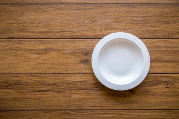 Empty white plate on wooden table Top View with Text Space