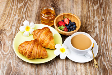 Cup of coffee and croissants on wooden background