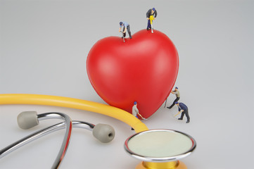 Miniature people with red heart and stethoscope