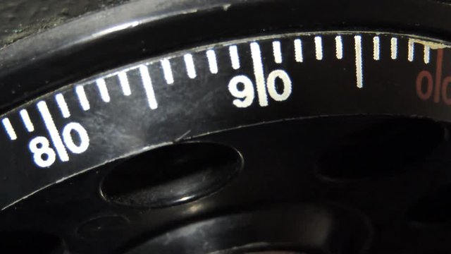 Safe combination lock on a stainless steel. Closeup image of torchlit hand turning a combination lock dial on a safe