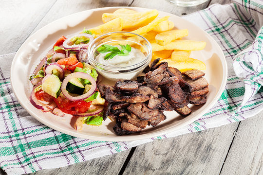 Grilled meat with French fries and fresh vegetables