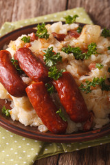 Dutch stamppot of potatoes, cabbage and carrots, with sausages closeup on a plate. vertical
