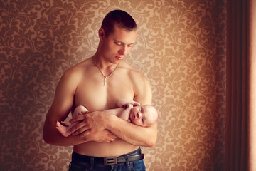 Young strong man holding a small fragile baby in her arms