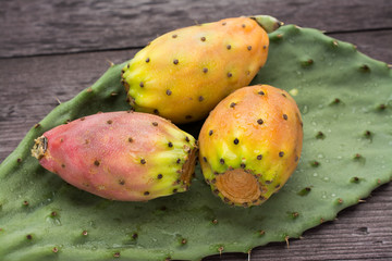 Fresh ripe whole prickly pears a leaf of the plant on wooden vin