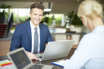 Obraz premium Successful business consultation. Portrait of investment advisor businesswoman sitting at office in front of laptop and consulting with executive professional business man