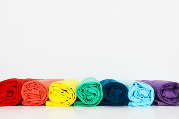 stack of colorful t-shirt rolled up on white background, copy space