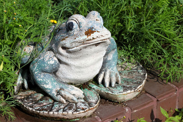 Shabby old frog statue in a garden.