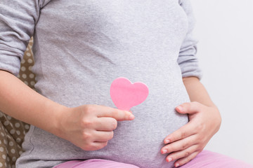 Pregnant woman and paper heart on her belly