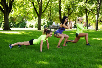 Females warming up on a lawn in summer park.