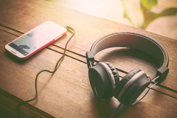 Headphones, and mobile phones placed on the wood in sunset background