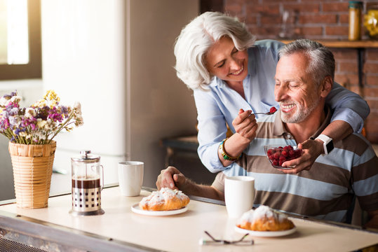 Elderly positive woman feeding her lovely husband.