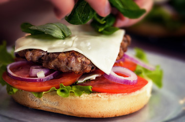 Chef  added basil in hamburger. Cooking burger concept