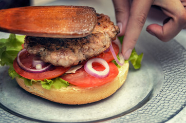 Chef  added cutlet in hamburger. Cooking burger concept