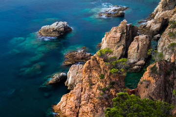 Sea with rocks and transparent water at sunrise, Town of Tossa de Mar, Spain
