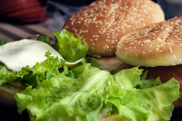 Lettuce and a slice of cheese on a bun with sesameseeds. Cooking burger concept