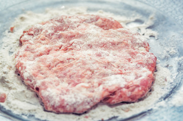 Cutlet for burger in  plate is sprinkled with flour. Cooking burger concept