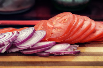 Slices onion and tomato on cutting board. Cooking burger concept