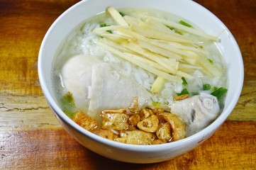 rice porridge with chicken leg topping slice ginger and fried garlic on bowl