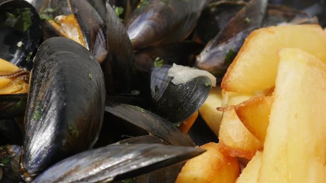 Tasty potato chips and Mytilus edulis sea food background 4K 2160p 30fps UltraHD footage - French fries and blue common mussels with lemon close-up 3840X2160 UHD video 