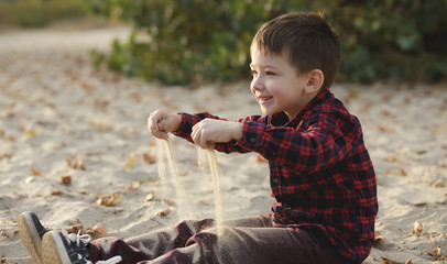 Little boy strewing sand outdoor