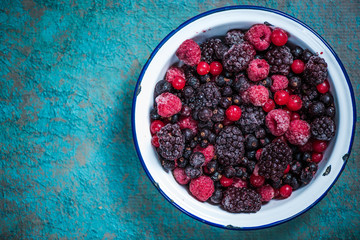 Frozen berries fruits in rustic bowl
