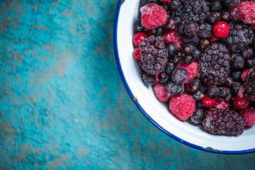 Frozen berries fruits in rustic bowl