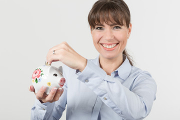 Fototapeta na wymiar Frau wirft Geld in ein Sparschwein