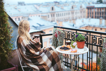 woman with tea sheltered blanket breakfast on the balcony overlooking the city