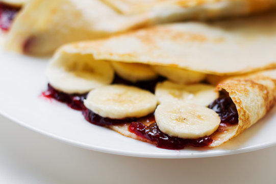 Homemade crepes with sweet fruit jam and banana slices. Breakfast concept