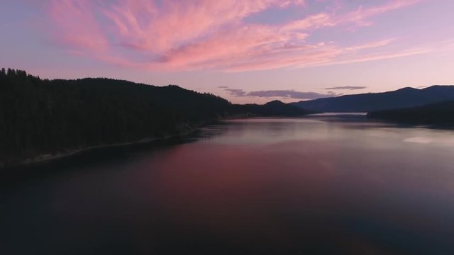 Aerial Flight Over Trees to Reveal Large Lake with Pink Sunset