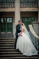 Obraz premium Unrecognizable young wedding couple holding hands as they enjoy romantic moments outside on the stairs. Man and woman kissing nature.