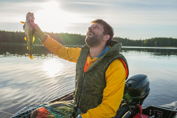 Handsome fisherman catched a haddock and looking to the sky