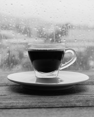 cup of coffee espresso on wooden table next to window. black and white
