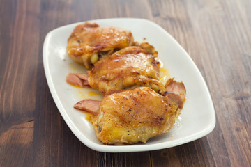 fried chicken with smoked meat on white plate on brown wooden background