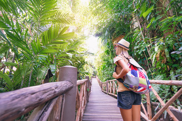 Travel concept. Back view of young woman with backpack outdoors discovering jungle.