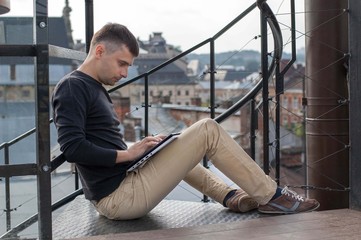 Man portrait with laptop on the background of the city.