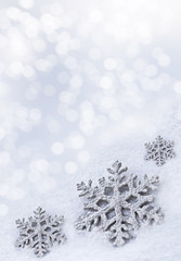 Glass toy snowflake on snow background.