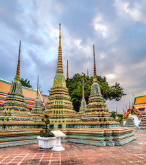 Classical Thai architecture in Wat Pho public temple at stormy sunset cloudy sky, Bangkok, Thailand. Wat Pho known also as the Temple of the Reclining Buddha.