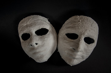 weiße Masken auf schwarzem Hintergrund
