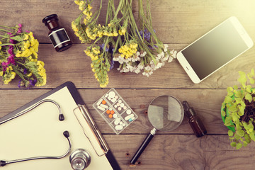 Obraz na płótnie Canvas Workplace of a doctor. Stethoscope, clipboard, pills, smartphone and other stuff on wooden desk