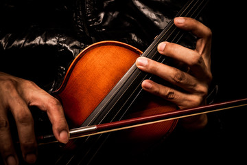 hands of musician in black jacket posing on classical violin