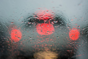 Raindrop on the window of the car. Abstract blur of car light.